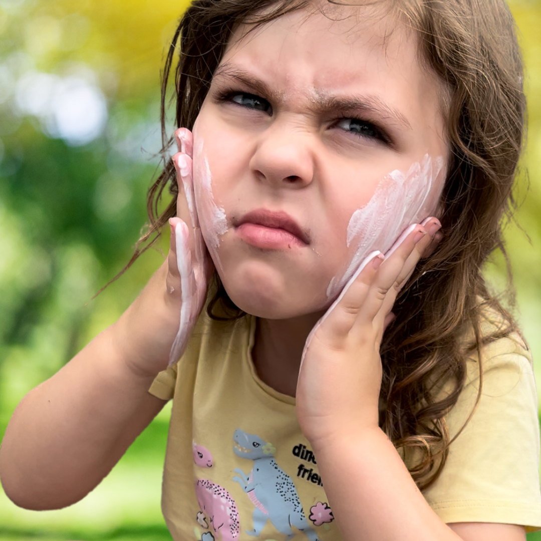 SUNNYBOD sunscreen applicator. Before and After. The Before image of a close up of a brunette girl who looks very cranky putting sunscreen on her face with her hands.