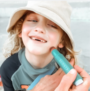 applying sunscreen to a boys face with a Sunscreen Applicator. 