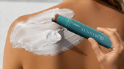 Close-up of SUNNYBOD sunscreen applicator brush applying sunscreen to a person’s back, with visible thick SPF spread across the shoulder during application.