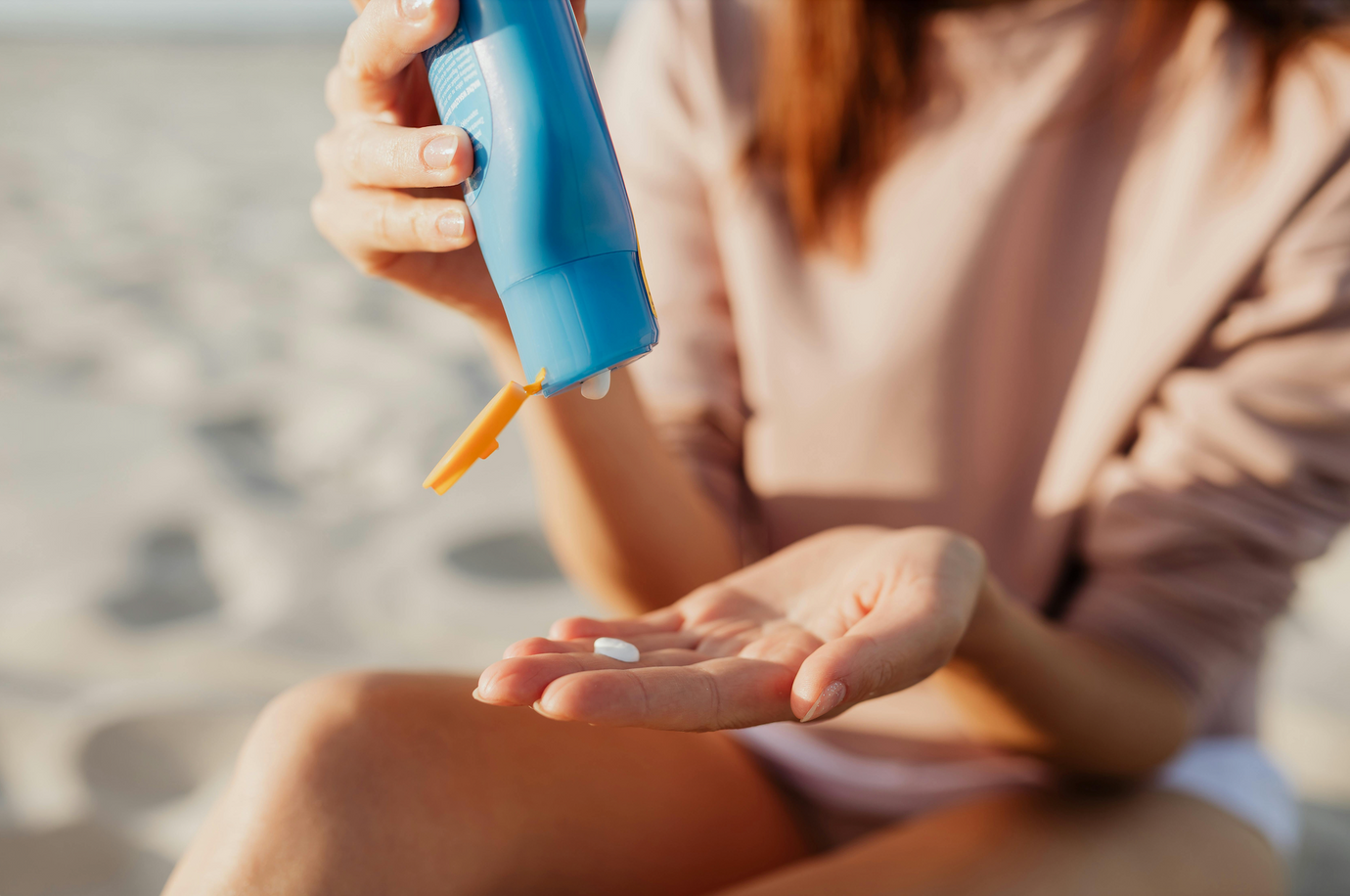 A close up of a hand with SPF being squeezed onto it outdoors. 