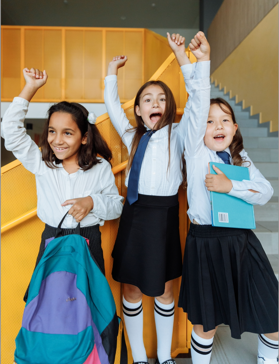 Three school children in uniform with school bags, illustrating a daily sunscreen routine for school kids.