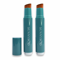 The picture shows The Friends Pack. Two SUNNYBOD™ Refillable Sunscreen Brush Applicator's side by side. The brush is turquoise. The susncreen brush bristles are light brown. The handle has the word "SUNNYBOD" written in white capital letters. There is also a turquoise cap next to the brush that can be placed on the brush to cover the bristles. The brush is placed on a white background.